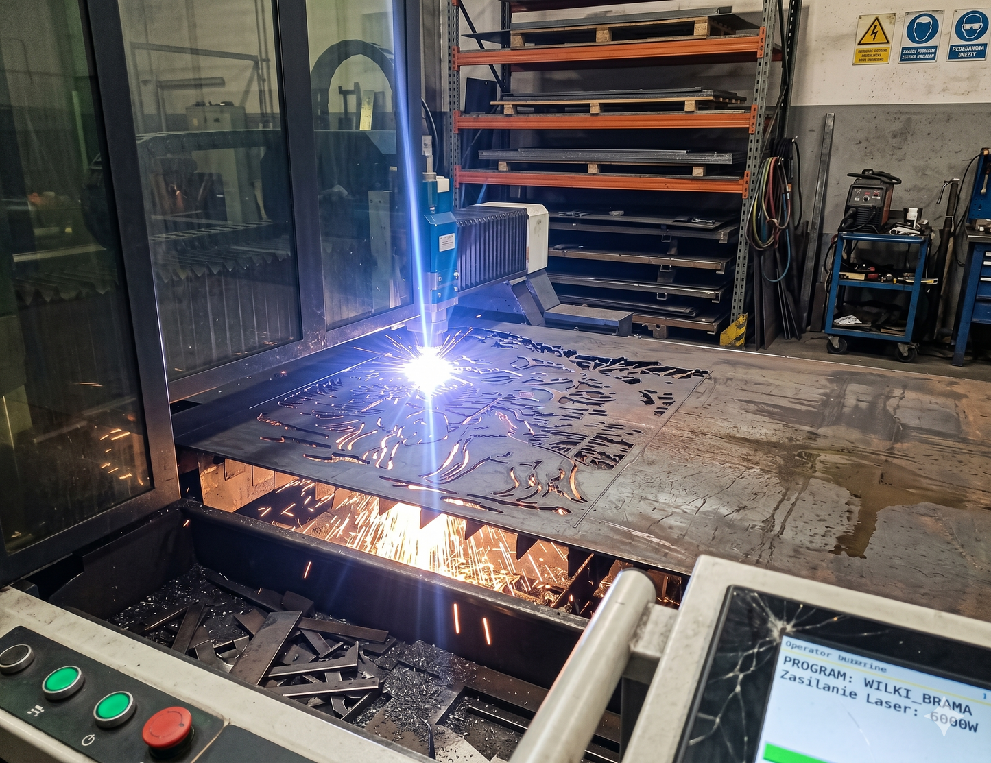 Industrial CNC laser cutting machine processing a metal panel with a wolf in forest design, showing the decorative gate manufacturing process.