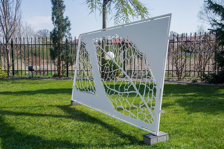Decorative metal screen with geometric design on a grassy area
