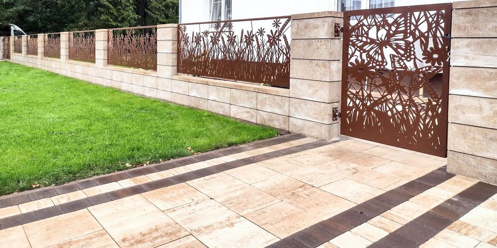 Garden with stone pathway, grass, and decorative metal gate.