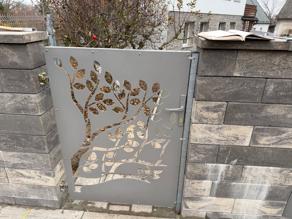 Decorative metal gate with tree design on a stone wall