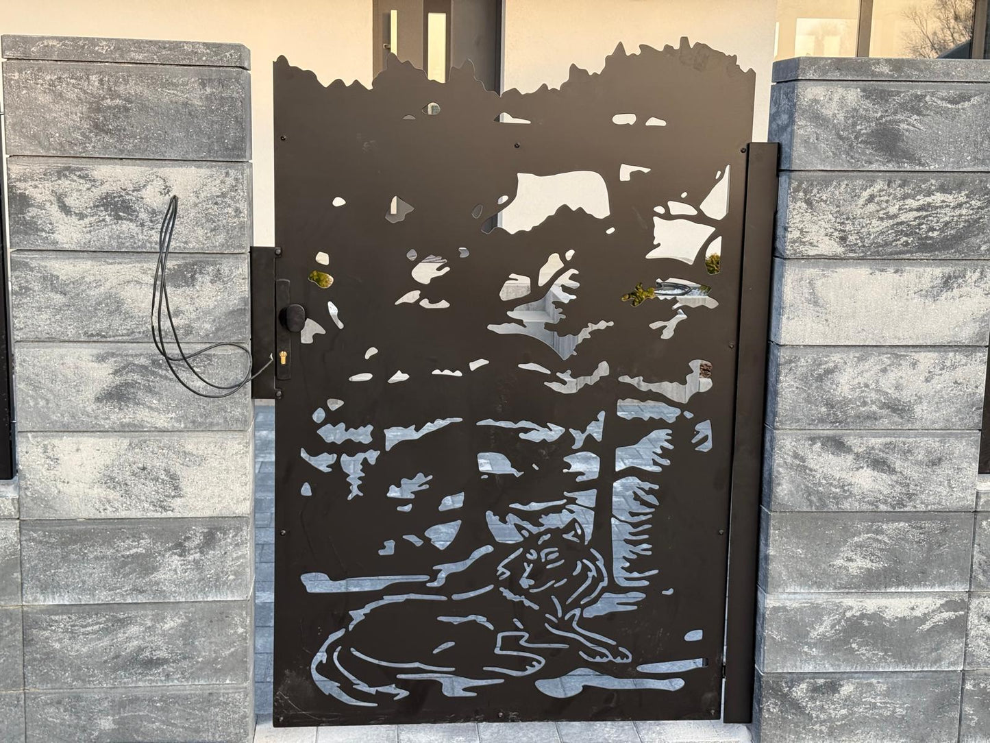 Decorative metal gate with a tiger design on a stone wall. wolf